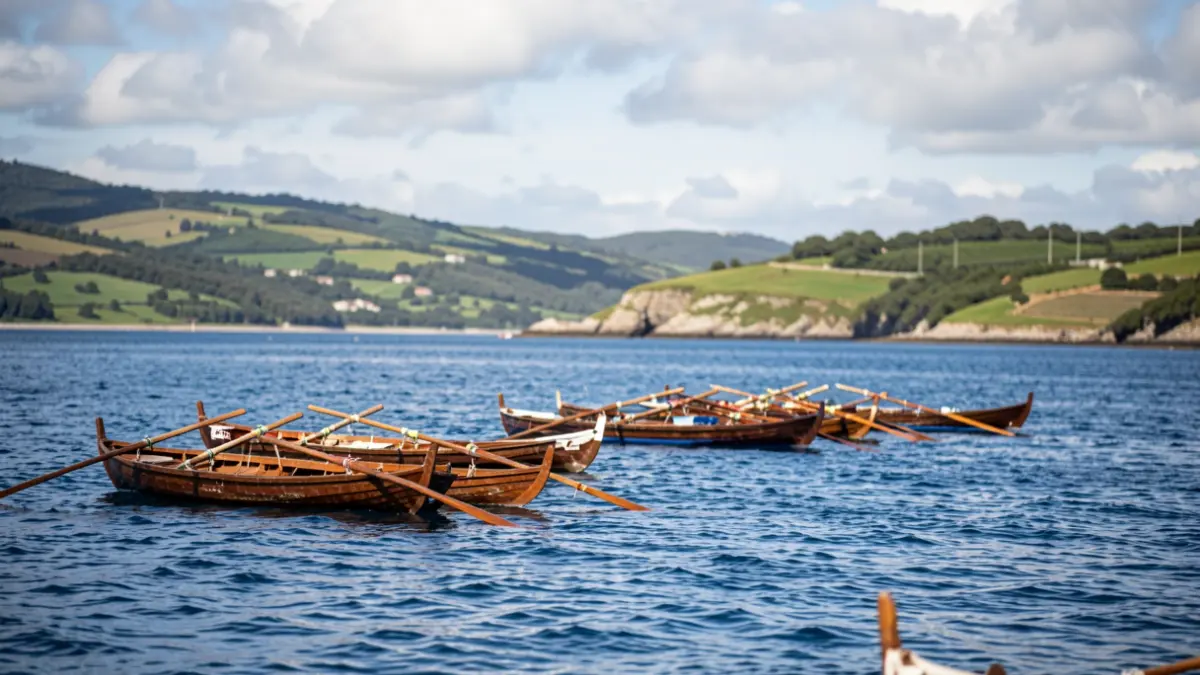 Imaxe xenérica de barcos de remo (traineras) nunha baía galega, listos para unha regata.